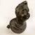 Bronze bust from the 17th century depicting a young boy with wavy hair and a robe gathered at the neck, ending in an oval...
