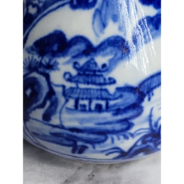 Vintage Asian Chinese flow blue and white porcelain vase. It features striking blue designs of a village scene with...
