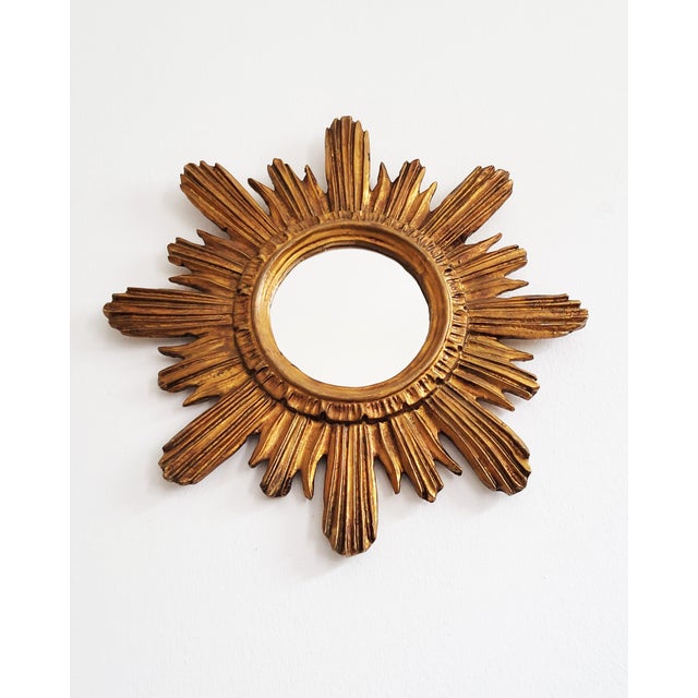 A highly decorative, gilded sunburst mirror from the 1950s, in very good condition. Elegant, intricately carved frame...