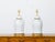 A pair of white porcelain lidded urns table lamps with single lights on circular gilded bases, wired for the USA. This...