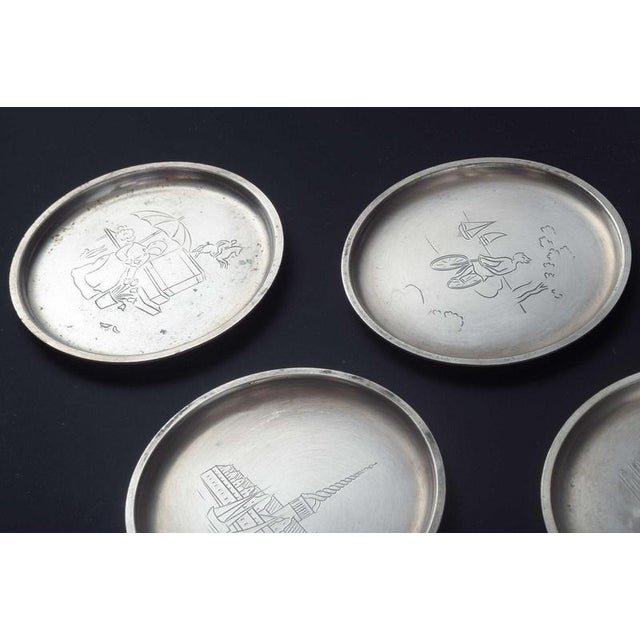 Just Andersen, Denmark. Set of seven pewter bottle coasters engraved with motifs from Denmark. Circular form with ribbed...