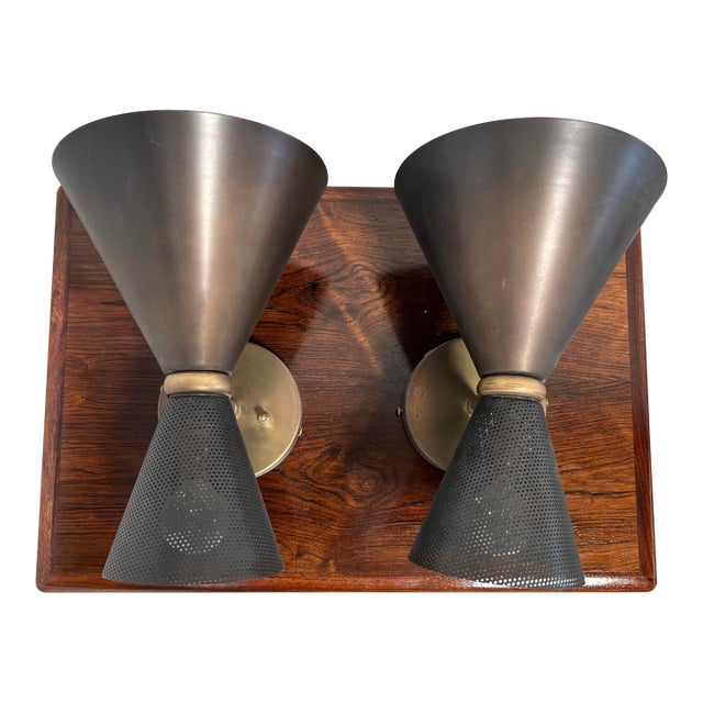 A pair of double cone/bowtie wall sconces with perforated black metal shades and aged brass mounts. Each fixture provides...