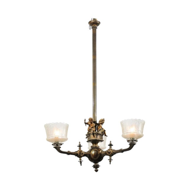 A French three-light bronze chandelier from the 19th century, with cherubs holding torches and Baccarat style crystal gas...