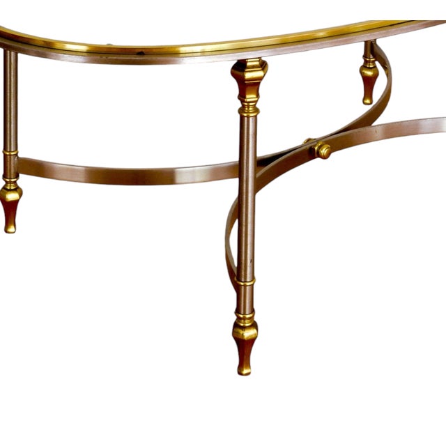 Featuring a sleek, transparent glass top set upon a striking frame of brass and chrome. In the sought-after style of...