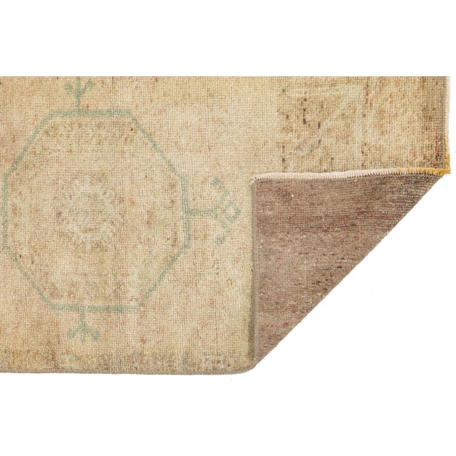 Elevate your space with this exquisite antique Turkish accent rug, featuring a soft, sun-faded palette of warm cream,...
