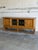 This architectural low console features a long rectilinear frame with a central pair of leaded glass doors. The balanced...