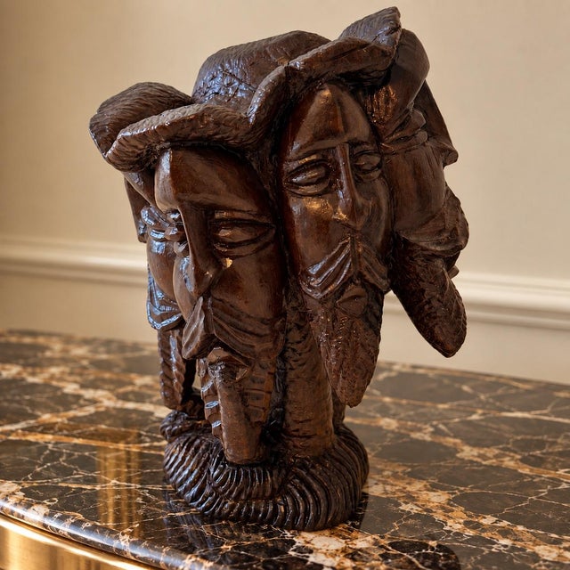 A striking metamorphic hand-carved hardwood sculpture in which seven expressive human faces come together to create the...