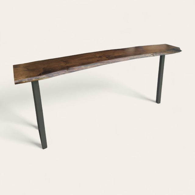 Oversized contemporary console table with a spalted maple slab top, finished in a dark tone that highlights the wood’s...