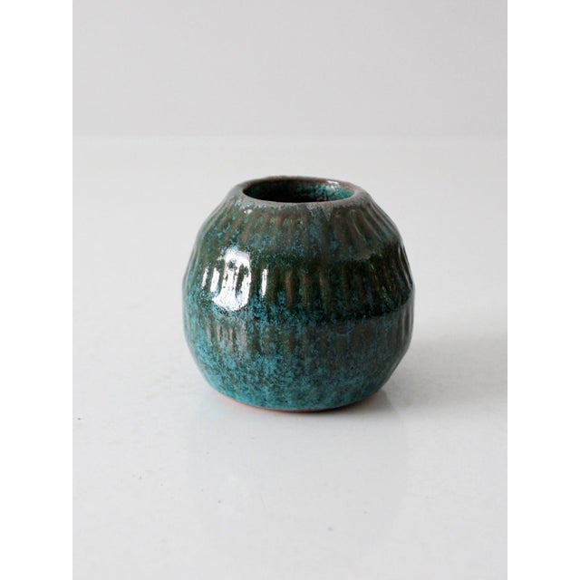 This vintage studio pottery vase features a flowing, organic form with a richly textured surface. The deep teal glossy...