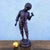 Beautiful bronze sculpture with a brown patina, depicting a young boy holding a spinning top. The bronze is titled "She's...
