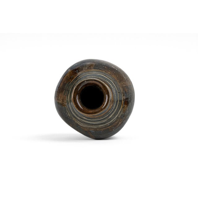 A studio vase decorated with bold strokes of black and brown glaze over a soft blue ground, recalling calligraphic or...