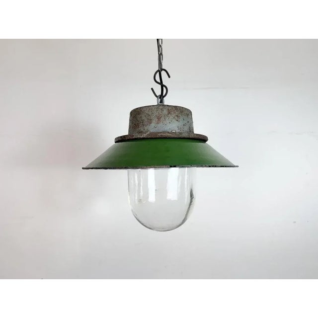 Industrial hanging lamp manufactured in Poland during the 1960s. It features a green enamel shade with a white enamel...