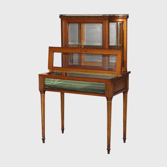 An antique French Louis XVI style vitrine, crafted circa 1920, showcases gilt wood with ormolu detailing. This display...