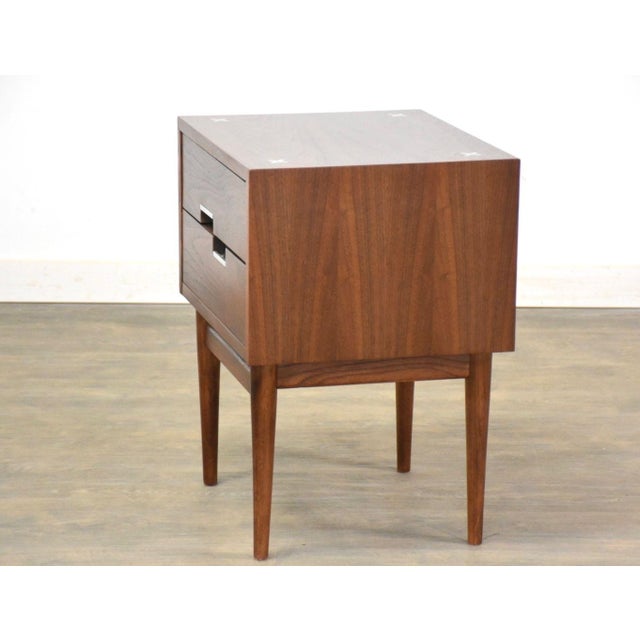 A mid century modern walnut two drawer nightstand with aluminum x inlay and off set aluminum pulls designed by Merton...