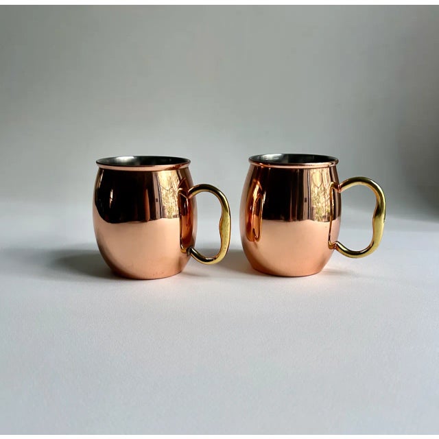 Vintage Pair of Brass Handled Copper Moscow Mule Mugs. Featuring a Copper Barrel shape with Stainless Steel Interior. Hold...