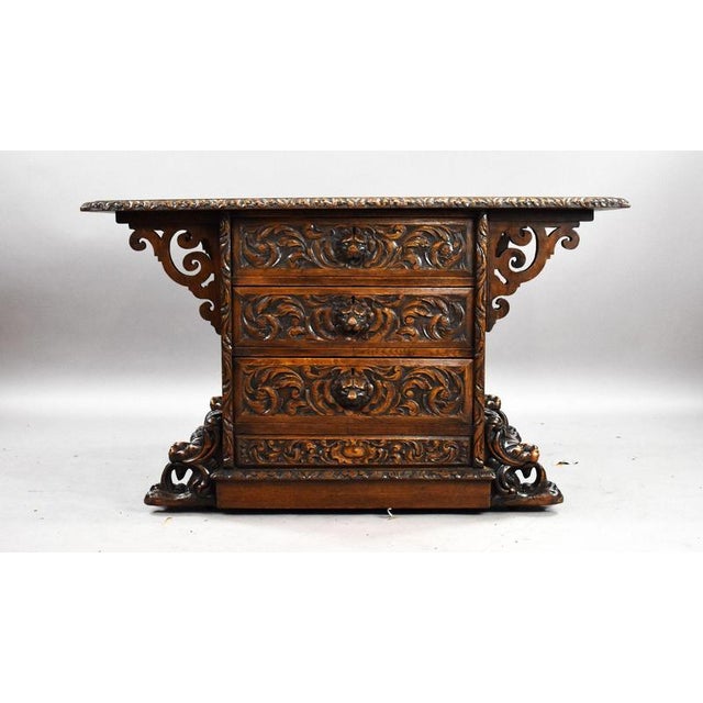 A highly decorative carved oak partners writing table, fitted with a green tooled leather writing surface and richly...