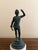 A Grand Tour–style classical figure in brass, mounted on a cylindrical marble base. The slightly more relaxed posture and...