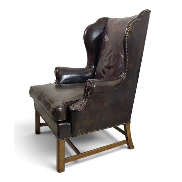 Handsome vintage wingback chair by Baker Furniture, upholstered throughout in richly patinated dark brown leather. The...