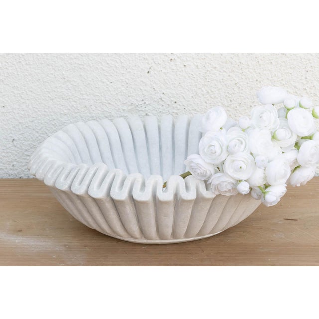 Carved from a single block of pristine white marble, the vessel has been meticulously hand-chiseled to create a continuous...