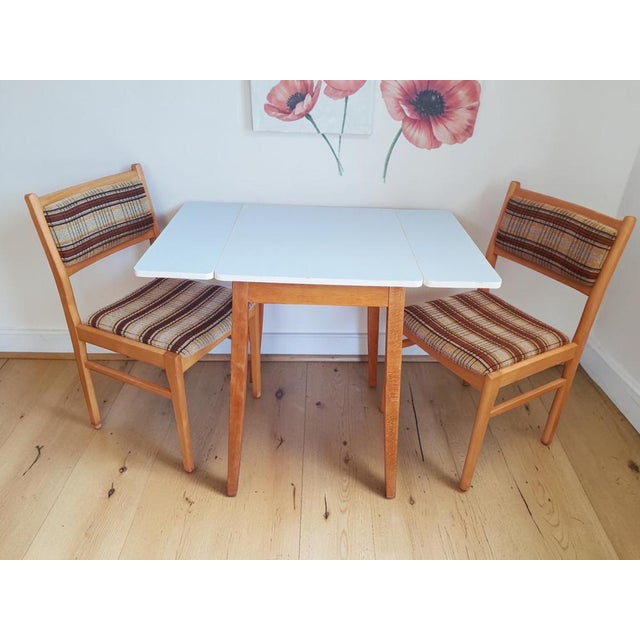 A stylish and practical vintage mid century dining set comprising a 1960s light blue formica drop-leaf kitchen table and a...