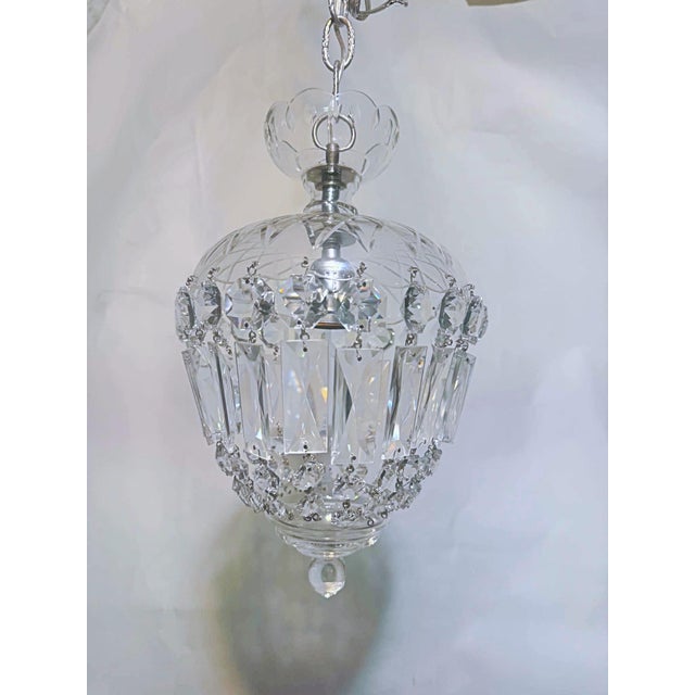 This elegant crystal hanging light features a rounded cage of vertically arranged faceted glass pieces that create a...