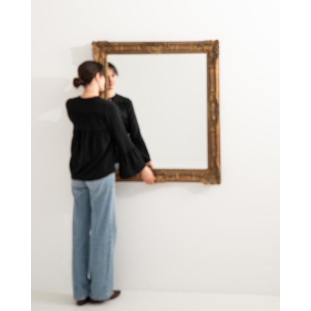 A 19th century French wall mirror in the Louis XV style, featuring a carved giltwood frame with flowing lines and soft...
