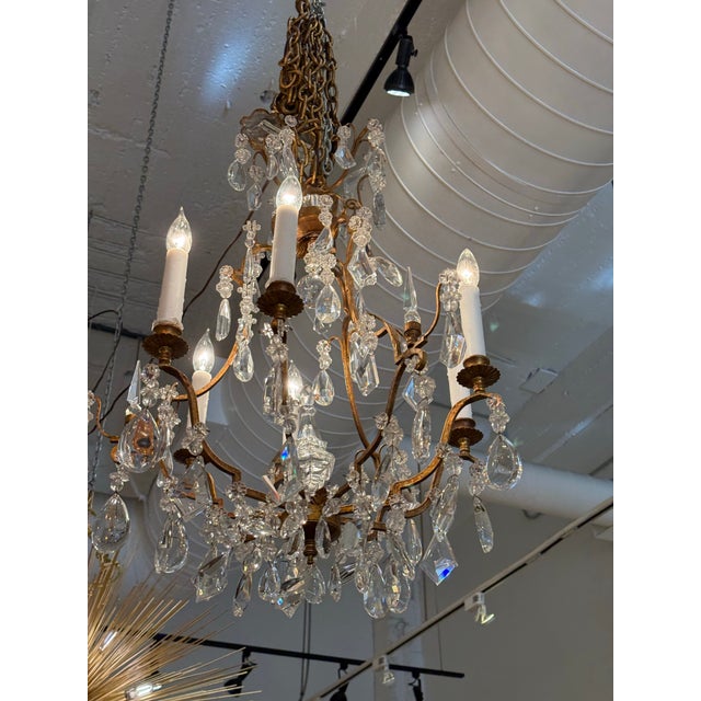 Design Plus Gallery presents a Crystal Chandelier. The chandelier has an antique gold metal frame with six lights and faux...