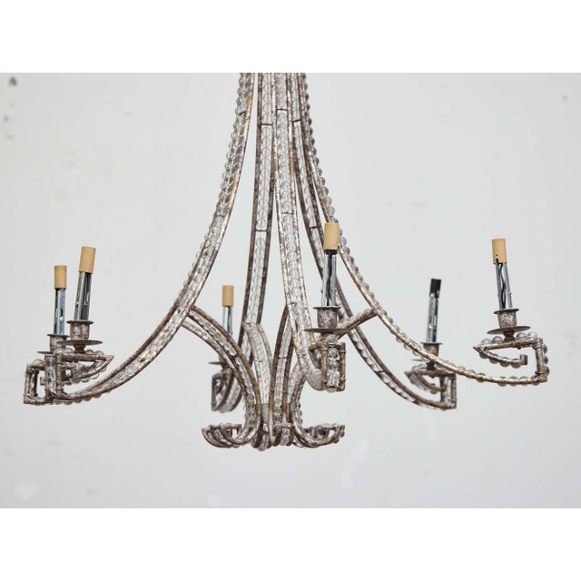 A French chandelier from the 19th century, crafted in hand-forged iron and richly detailed with strings of cut glass...