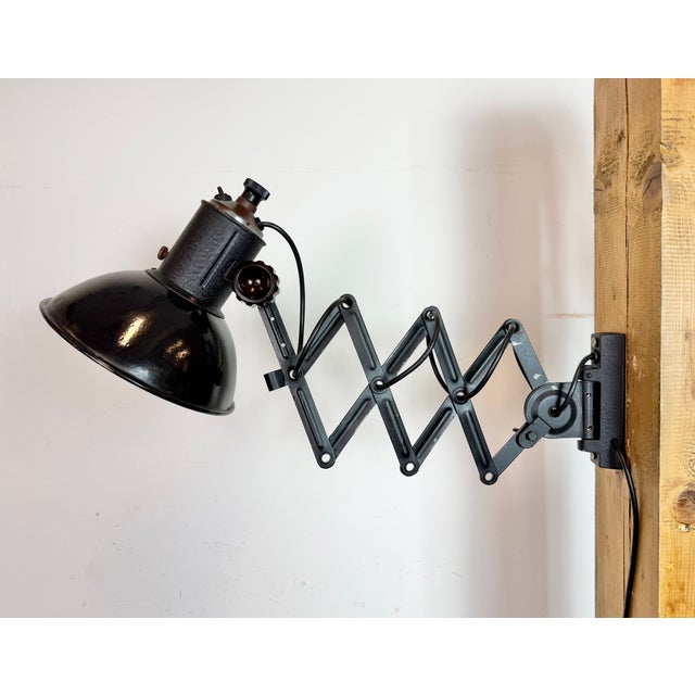 This vintage Industrial adjustable scissor wall lamp was produced in former Czechoslovakia during the 1950s. The lamp has...