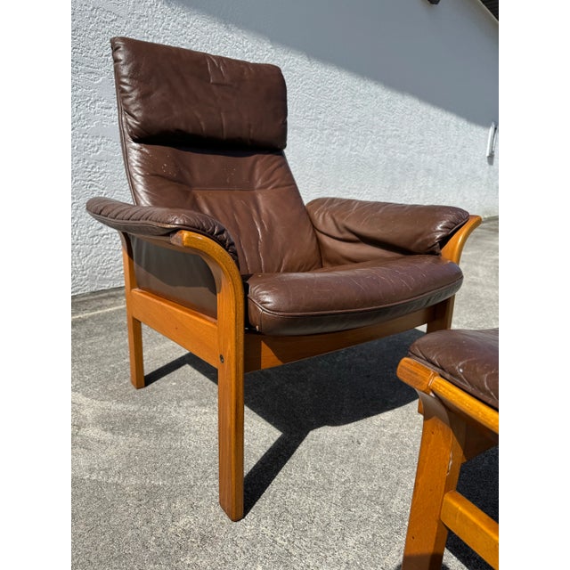 Crafted in the 1970s, this high-back armchair features supple brown leather upholstery paired with a sculpted solid teak...