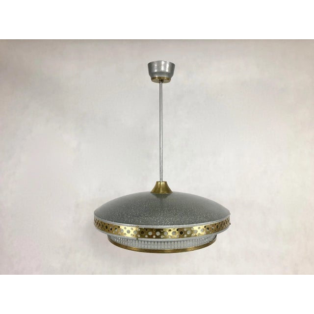 The ceiling lamp was manufactured by L'udib from Bratislava in the 1950s. The upper part and lower rim of the saucer are...
