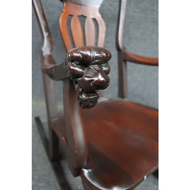 An antique Horner-style rocking chair crafted in mahogany, featuring carved lion head arm terminals, a pierced splat back,...