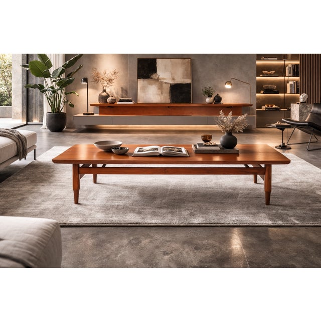 An elegant solid teak coffee table featuring a minimalist design and a bold construction. The rectangular top interacts...