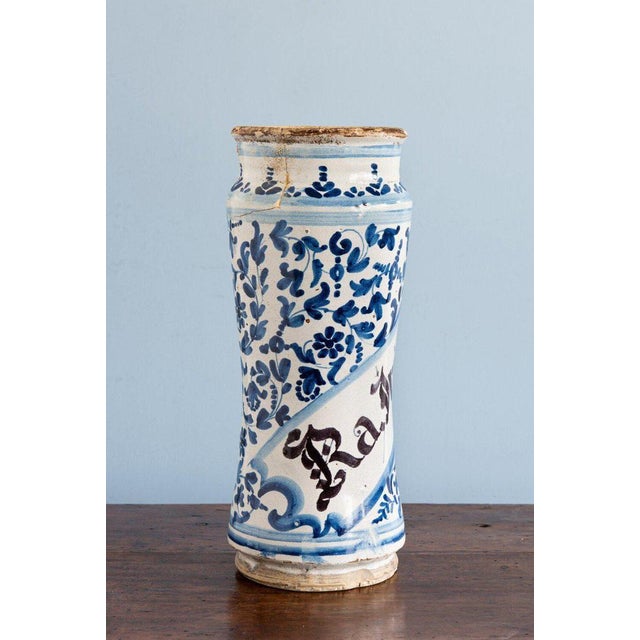 An 18th-century Spanish albarello jar from Catalonia, decorated with a scrolled label bearing elegant black lettering,...