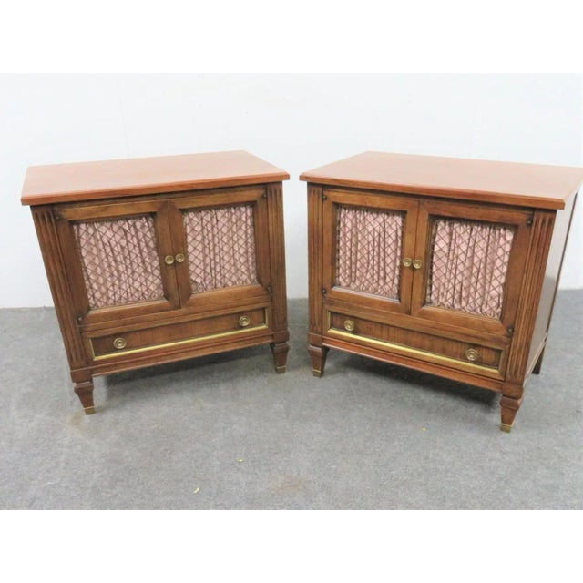A pair of John Widdicomb nightstands. Italian style. Made of solid cherry wood. Boasts 2 doors, a single drawer, wire...