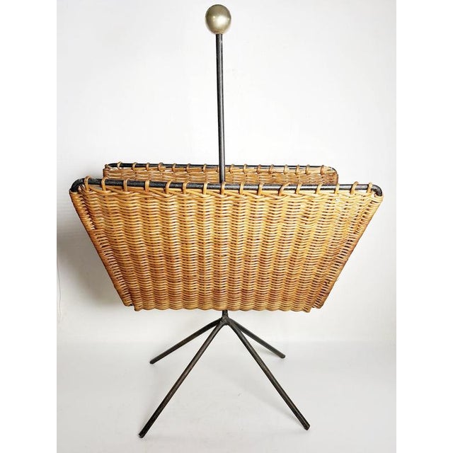 French magazine rack dating from the 1950s, combining woven rattan with a black metal structure and brass details. The...
