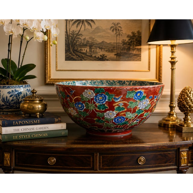 A striking large-scale Japanese porcelain centerpiece bowl executed in the Kutani taste, featuring richly hand-painted...