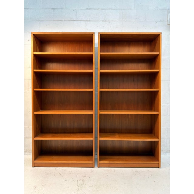 Pair of vintage teak bookcases by Sun Cabinet Co., featuring warm teak tones, beautiful natural wood grain, and a clean,...