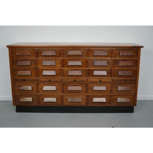 This apothecary / shop cabinet was produced during the 1930s in Germany. It features 25 drawers with oak handles and three...