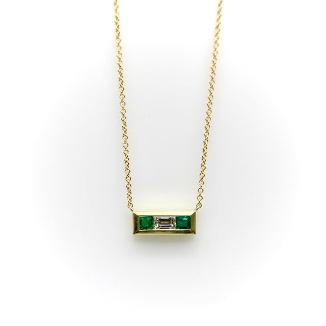 This beautifully bezel set pendant features two square cut emeralds and a diamond baguette. They are elegantly placed to...