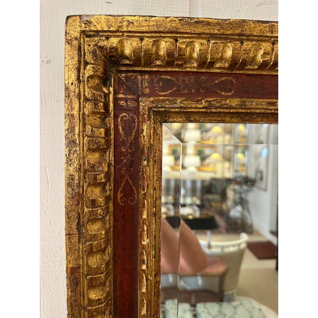 Classic antique Italian rectangular mirror having carved gilded wood frame with red underpaint and old world decoration.