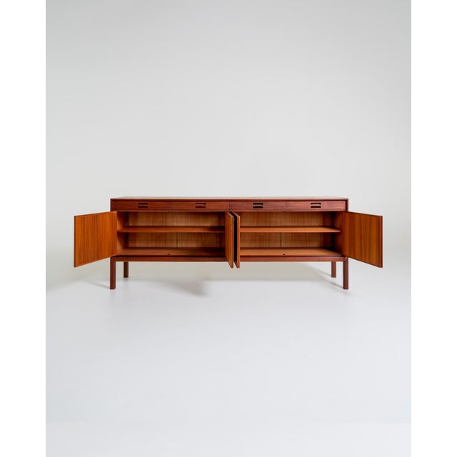 Teak sideboard with four upper drawers featuring distinctive recessed handles and four doors enclosing compartments with...