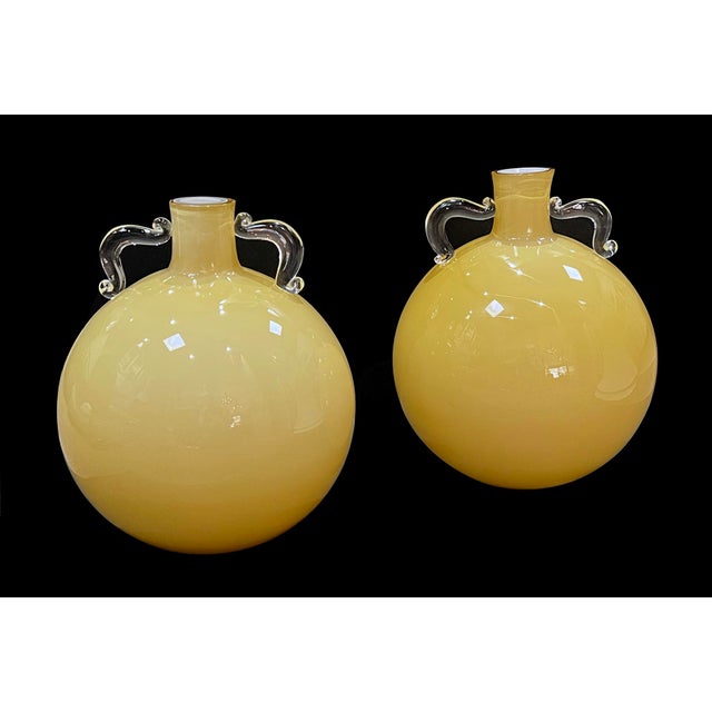 each exceptionally large hand-blown vessel with short neck flanked by clear double handles over a large spheroid body;...