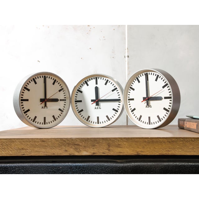 A factory wall clock by aeg from the 1960s in its original hammered grey paint, with a light dial, bold black bar markers,...