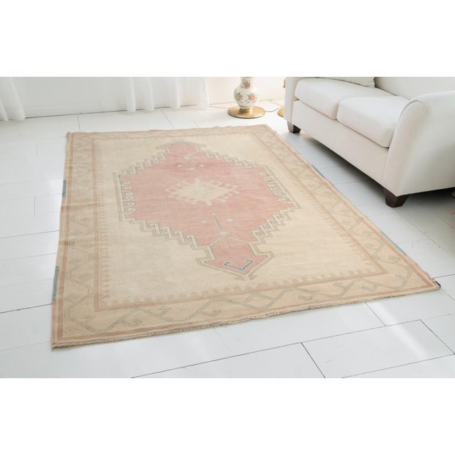 This is a vintage Turkish Oushak rug from the Mid 20th Century. The piece was hand-knotted.