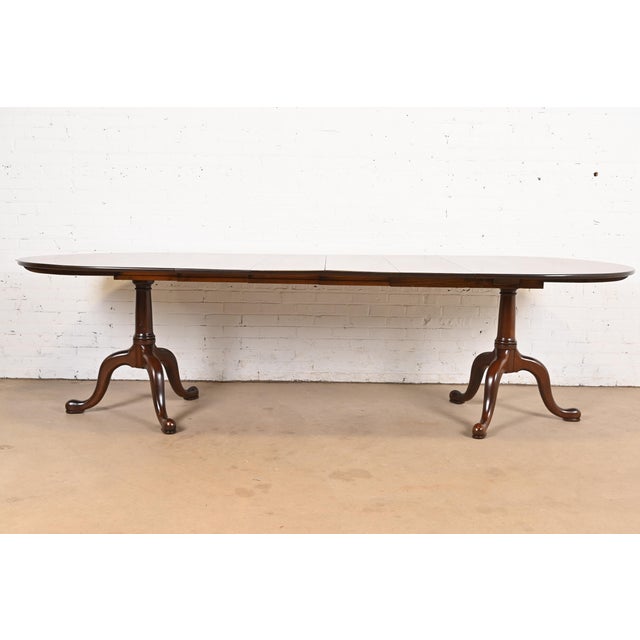 A gorgeous Georgian, Regency, or Queen Anne style solid mahogany double pedestal extension dining table By Henkel Harris...