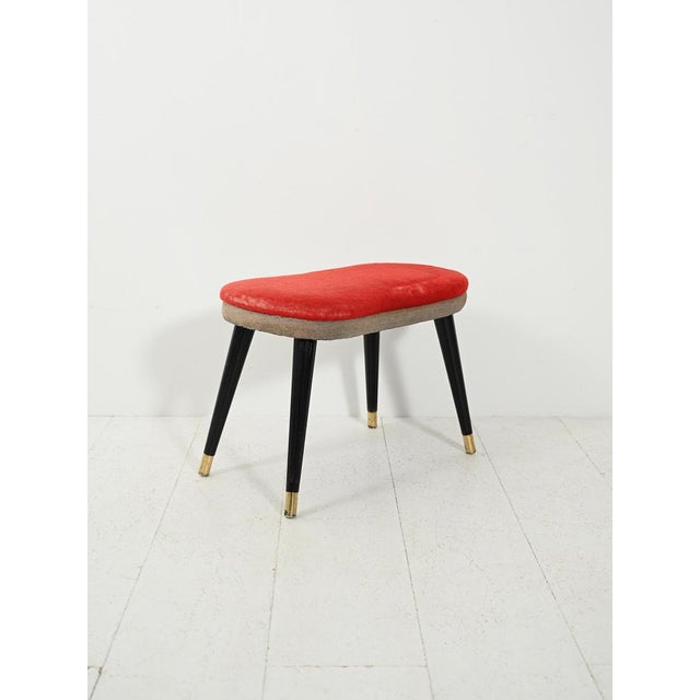 Vintage 1950s stool with a two-tone red velvet and gray fabric seat, turned black legs, and brass tips. The organically...