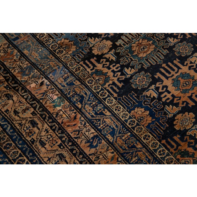 This room-sized antique Hamadan hand-knotted wool rug features a dark blue field. It showcases a stunning allover floral...