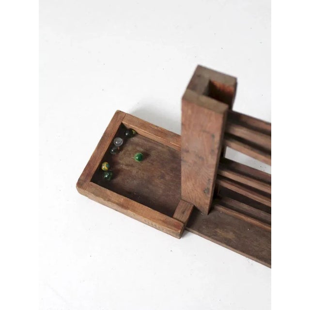 A vintage marble run toy dating to the early 20th century, crafted from hand-finished wood with sloping ramps designed to...