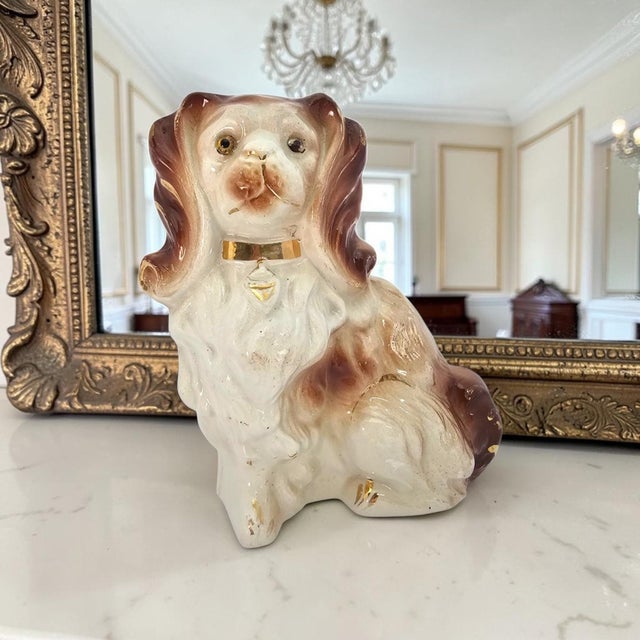 A late nineteenth-century English Staffordshire pottery mantel figure modelled as a seated King Charles-type spaniel,...